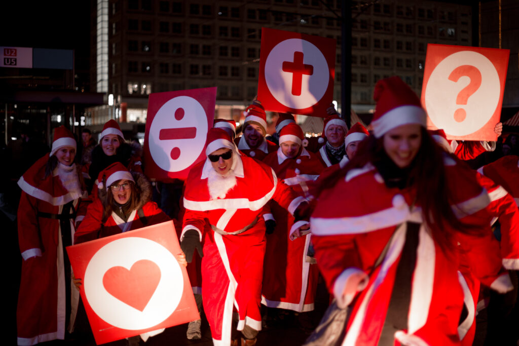 Weihnachtsmänner und -frauen mit Schildern