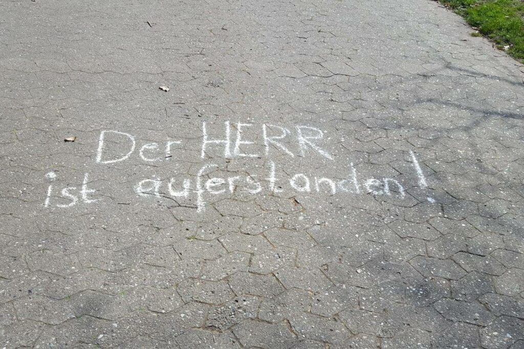 "Der Herr ist auferstanden" steht mit Kreide auf dem Asphalt