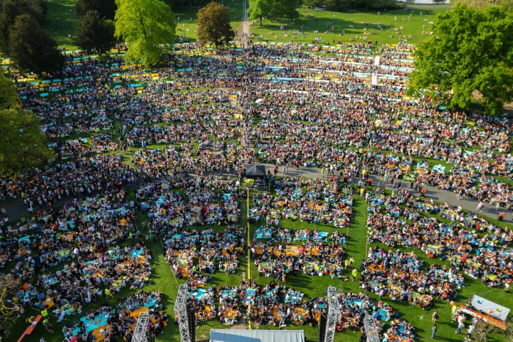 Viele Menschen sitzen auf einer Wiese.